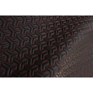 Puede incluir: Primer plano de una tela negra con un patrón geométrico. El patrón está formado por formas tridimensionales repetidas, con costuras rojas que delinean cada forma. La tela tiene una apariencia texturizada.