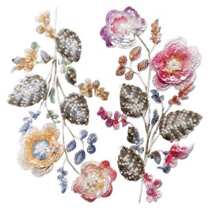 May include: Embroidered floral applique with a variety of colors. The design features flowers in shades of pink, purple, and yellow, with silver and gold accents. The leaves are a mix of silver and grey. The applique is likely for clothing or craft projects.