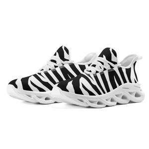 May include: Pair of trainers with a black and white zebra stripe design. The shoes have white soles and laces. The design features a breathable mesh upper and a cushioned sole for comfort and support.