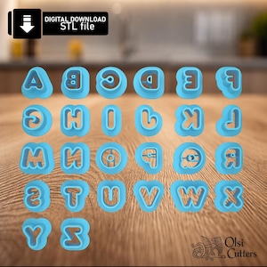 Puede incluir: Un conjunto de cortadores de galletas de plástico azul claro con las letras de la A a la Z. La imagen incluye una etiqueta rectangular negra con un icono de flecha blanca y el texto DIGITAL DOWNLOAD STL file, y un logo Olsi Cutters.