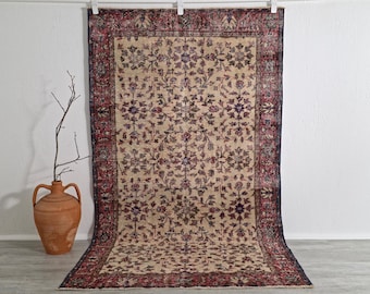 May include: A rectangular, vintage rug with a cream-colored field and a detailed floral pattern in shades of burgundy, navy, and purple. The rug has a burgundy border with intricate designs, adding a touch of elegance to the overall aesthetic.