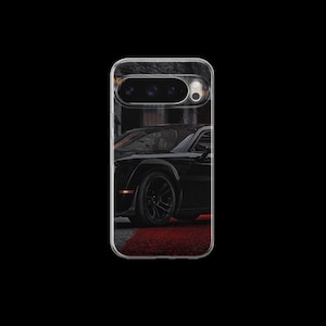 Könnte beinhalten: Transparente Handyhülle mit einem schwarzen Sportwagen auf einer rot-grauen Oberfläche. Das Auto hat schwarze Räder und ein schlankes Design. Die Hülle hat einen transparenten Rand und einen Kameraausschnitt.