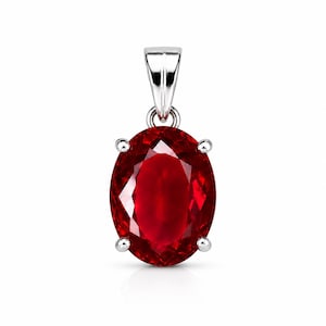 May include: An oval-cut deep red gemstone pendant set in a polished silver-toned metal prong setting. The faceted stone features a brilliant crimson hue, secured by four small prongs and attached to a tapered silver-toned metal bail at the top.