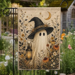 May include: A rectangular garden flag featuring a cream-colored background with a central illustration of a ghost wearing a black witch hat, holding a lit lantern, and surrounded by various brown and yellow wildflowers under a crescent moon and stars.