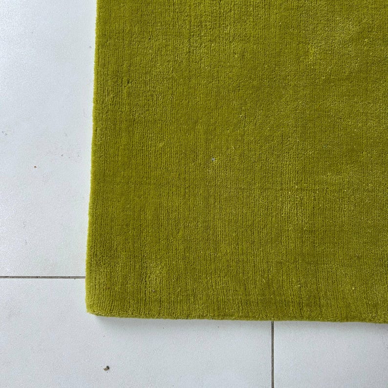 K&ouml;nnte beinhalten: Ein rechteckiger Teppich in einem einfarbigen Chartreuse-Gr&uuml;n mit einer dichten, kurzflorigen Textur. Der Teppich hat gerade, saubere Kanten und eine gleichm&auml;&szlig;ige Oberfl&auml;chenbeschaffenheit, die einen konsistenten, lebendigen Gr&uuml;nton zeigt.