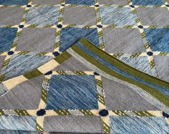 May include: A woven textile featuring a repeating grid pattern of alternating light gray and deep blue squares. The squares are separated by thin, diagonal-striped bands in olive green and cream, accented with small, dark blue circular dots.