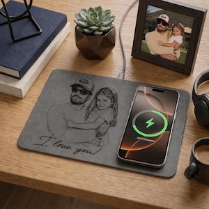 May include: A rectangular gray wireless charging pad featuring a laser-engraved illustration of a person holding a child, with the text "I love you!" written in cursive. A smartphone is placed on the pad, displaying a green charging icon.