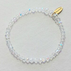 May include: A clear crystal bracelet with a gold clasp and a small gold tag that says "Navenadia".