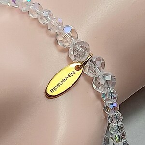 May include: A clear crystal bracelet with a gold charm that says "N.Y.enadid".