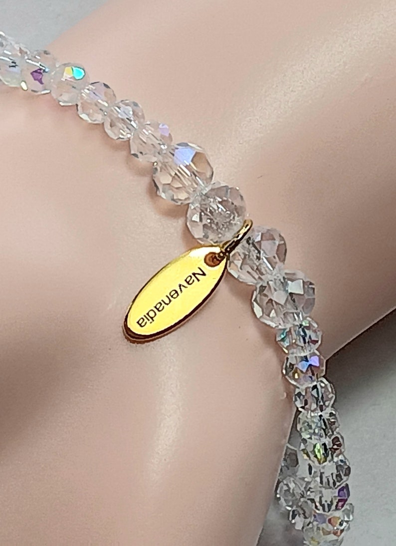 May include: A clear crystal bracelet with a gold charm that says "N.Y.enadid".