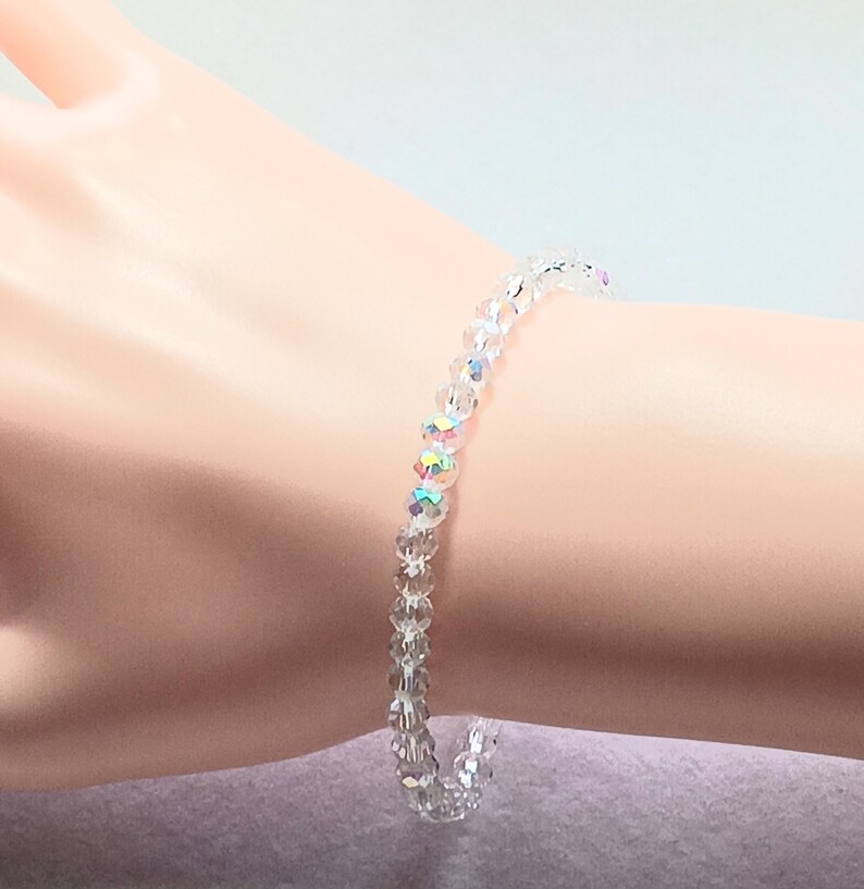 May include: A delicate bracelet made of clear crystal beads. The beads have a subtle iridescent shimmer.