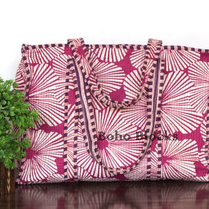 Könnte beinhalten: Große Tragetasche mit einem sich wiederholenden fächerartigen Muster in Weiß und Magenta. Die Tasche hat zwei Griffe und eine dunkelviolette Bordüre. Der Text "Boho Blocks" ist auf der Tasche zu sehen.