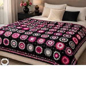 May include: A black and pink crocheted blanket with a floral pattern, displayed on a bed. The blanket features a repeating design of pink, white, and gray circles against a black background. The bed is made with white sheets and pillows.