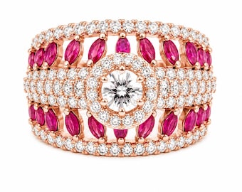 Puede incluir: Un anillo de oro rosa con un diamante central de talla brillante redonda rodeado por un halo de diamantes blancos más pequeños. La banda es ancha e incorpora filas de rubíes rosa vibrante talla marquesa y diamantes blancos en pavé.