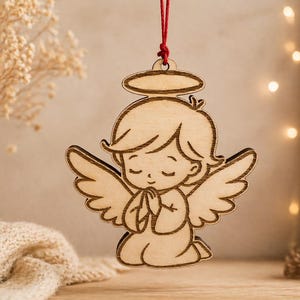 Könnte beinhalten: Holzengel-Ornament mit Heiligenschein, Flügeln und gefalteten Händen. Der Engel kniet mit geschlossenen Augen. Er hängt an einer roten Schnur. Das Ornament ist aus hellem Holz mit natürlicher Oberfläche gefertigt.