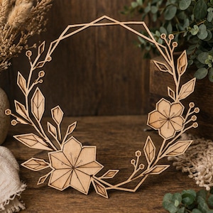 Könnte beinhalten: Ein floraler Holzkranz mit geometrischen Akzenten. Der Kranz zeigt lasergeschnittene Blumen, Blätter und einen geometrischen Rahmen. Die natürliche Holzfarbe und das filigrane Design schaffen ein rustikales Dekorationselement, ideal für die Inneneinrichtung.