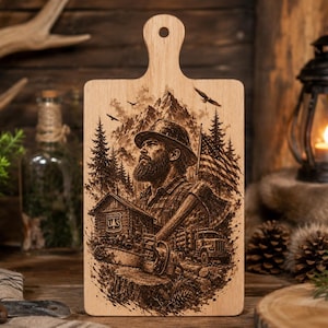 Könnte beinhalten: Ein rechteckiges Holzschneidebrett mit Griff und Aufhängeloch. Die Oberfläche zeigt eine detaillierte, dunkelbraune Lasergravur einer bärtigen Person mit Hut, einer Hütte, einer Kettensäge, einem Lastwagen und einer amerikanischen Flagge.
