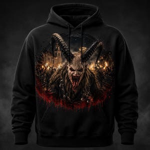 Könnte beinhalten: Schwarzer Kapuzenpullover mit einem detaillierten Grafik eines gehörnten Dämons mit langer Zunge, vor dem Hintergrund eines Gebäudes und einer Menschenmenge. Das Design umfasst rote Akzente und Ketten und erzeugt eine dunkle, gotische Ästhetik.