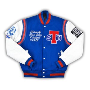May include: A blue and white varsity jacket with red accents. The jacket features the letters "STU" in red and blue, along with text that reads "Historically Black College Established in 1912." The sleeves are white, and the jacket has a snap-button closure.
