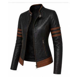 Puede incluir: Chaqueta de cuero sint&eacute;tico negra con detalles marrones. La chaqueta tiene cuello alzado, cremallera frontal y rayas marrones en las mangas. El cuello y el dobladillo tambi&eacute;n son marrones. Una prenda de abrigo elegante.
