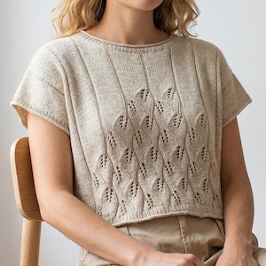 Può includere: Top in maglia beige a maniche corte con scollo tondo. La parte anteriore del top presenta un motivo traforato a forma di foglia e dettagli a coste verticali. Le maniche sono leggermente svasate e lo stile è casual e confortevole.