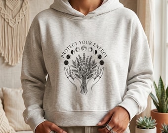 Felpa con cappuccio in cotone biologico "Proteggi la tua energia" con fasi lunari, stile stregonesco boho e celeste.