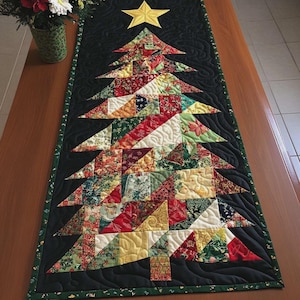 May include: A rectangular quilted table runner featuring a central Christmas tree design composed of various multicolored fabric patches. The tree is set against a black background with swirling stitch patterns and topped with a yellow star.