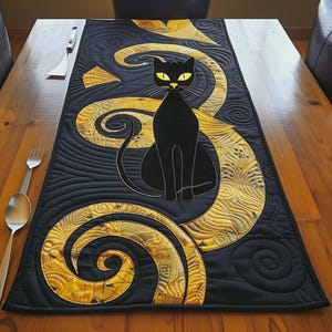 Può includere: Un runner da tavola rettangolare in tessuto raffigurante un gatto nero con occhi gialli centrato su uno sfondo scuro. Il design presenta motivi a spirale giallo oro con complesse cuciture trapuntate su tutta la superficie del tessuto.