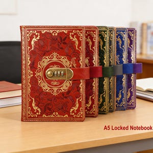 May include: A row of A5 locked notebooks in various colors, including red, green, blue, and purple. The red notebook is in the front and has a gold floral design and a combination lock. Each notebook has a leather strap.