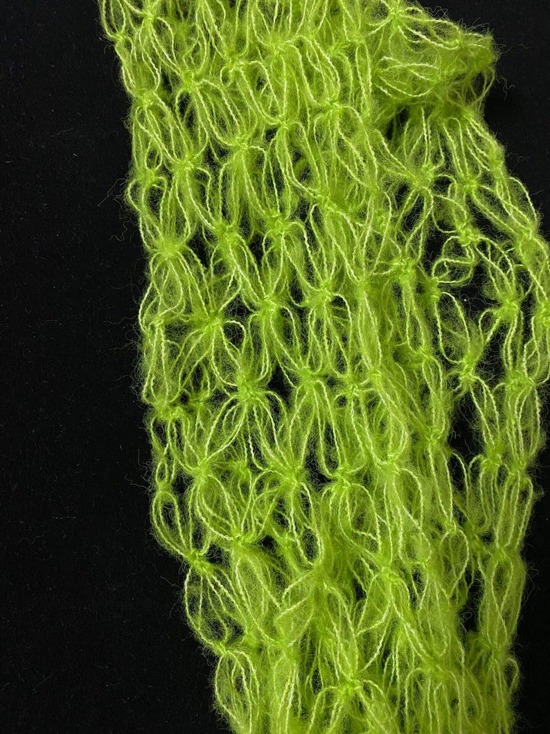 Peut inclure: Gros plan sur un textile vert n&eacute;on &agrave; tissage ouvert. Le tissu a un aspect d&eacute;licat et a&eacute;r&eacute; avec un motif floral r&eacute;p&eacute;titif. La couleur vive et le design ouvert sugg&egrave;rent une &eacute;charpe ou un ch&acirc;le l&eacute;ger, sur fond noir.