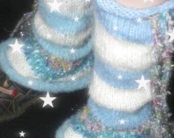 Peut inclure: Une paire de jambières tricotées avec des rayures horizontales bleu clair et blanches. Le modèle présente des accents de fil texturé multicolore et une bordure duveteuse. Les jambières sont portées sur des chaussures sombres avec des étoiles.