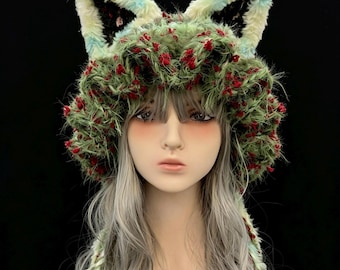 May include: A whimsical, handmade hat with faux fur fox ears. The hat features a green, textured crown adorned with red accents. The ears are trimmed with black, white, and blue faux fur. The hat is designed to be worn as a costume or fashion accessory.