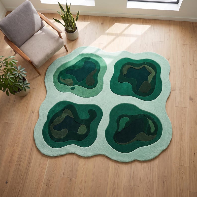 Pu&ograve; includere: Un grande tappeto dalla forma irregolare caratterizzato da una base verde menta chiaro con quattro distinti ritagli di forma organica in varie tonalit&agrave; di verde bosco, smeraldo e oliva scuro, creando un aspetto simile a una mappa topografica.