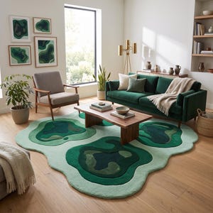 Pu&ograve; includere: Un tappeto dalla forma organica irregolare con motivi stratificati in stile topografico in varie tonalit&agrave; di verde, che vanno dal verde menta chiaro al verde bosco scuro, posizionato su un pavimento in legno chiaro in un soggiorno.