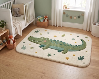 Può includere: Un tappeto rettangolare con sfondo color crema caratterizzato da una grande grafica di un coccodrillo verde testurizzato. Il design include piccole foglie verdi, stelle gialle e punti sparsi sulla superficie, creando un motivo giocoso ispirato alla natura.