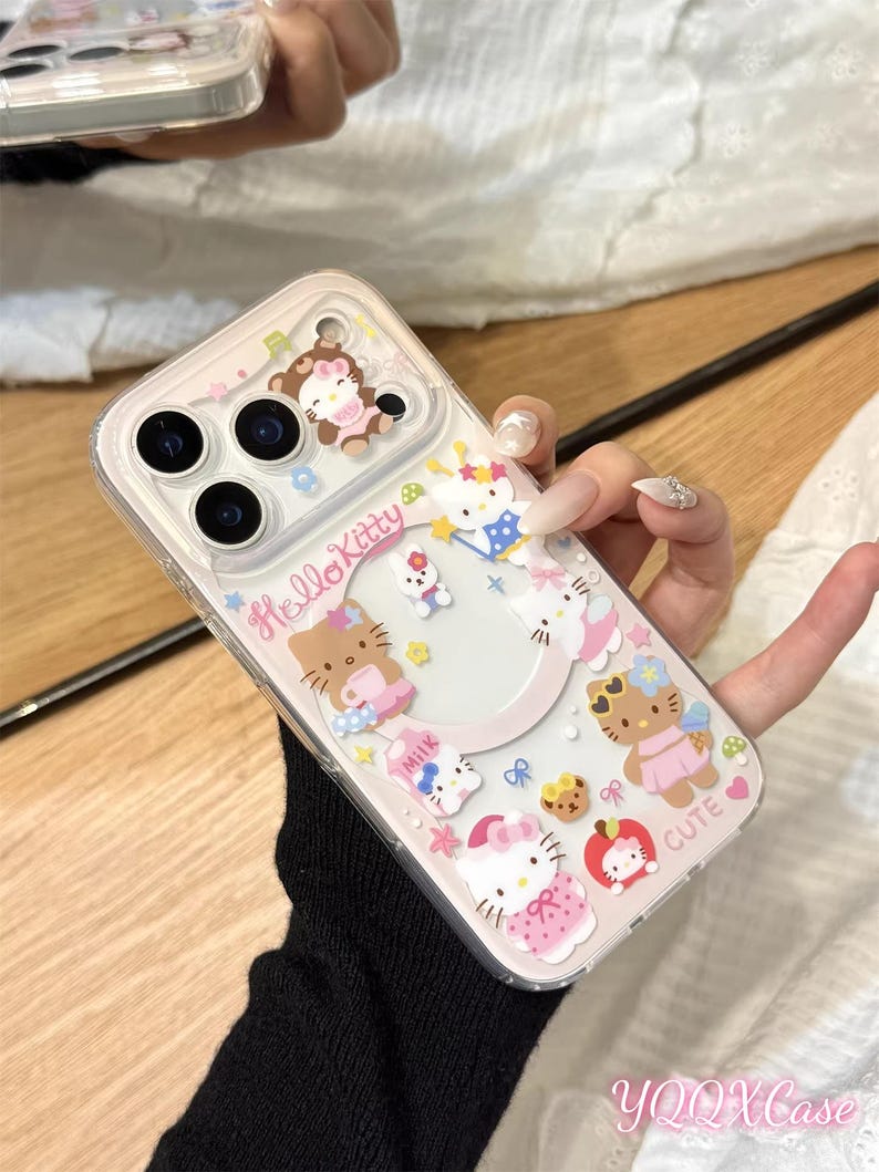 以下が含まれることがあります： 様々な衣装やアクセサリーを身につけたハローキティのキャラクターが飾られた透明な携帯電話ケース。ケースはピンクと白を基調とし、「Hello Kitty」と「Cute」の文字がデザインされています。