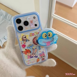 May include: Clear phone case with a blue border and colorful Zootopia character stickers. A blue frog-shaped phone grip is attached. The case features characters like Nick Wilde, Judy Hopps, and others. The text "Where is Gary?" is visible.