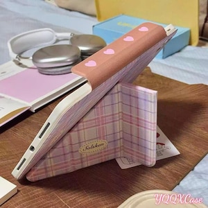 May include: A white ceramic mug with a black handle and the text "But First, Coffee" in a bold, black font. The mug is set against a blurred background, suggesting a cozy setting.