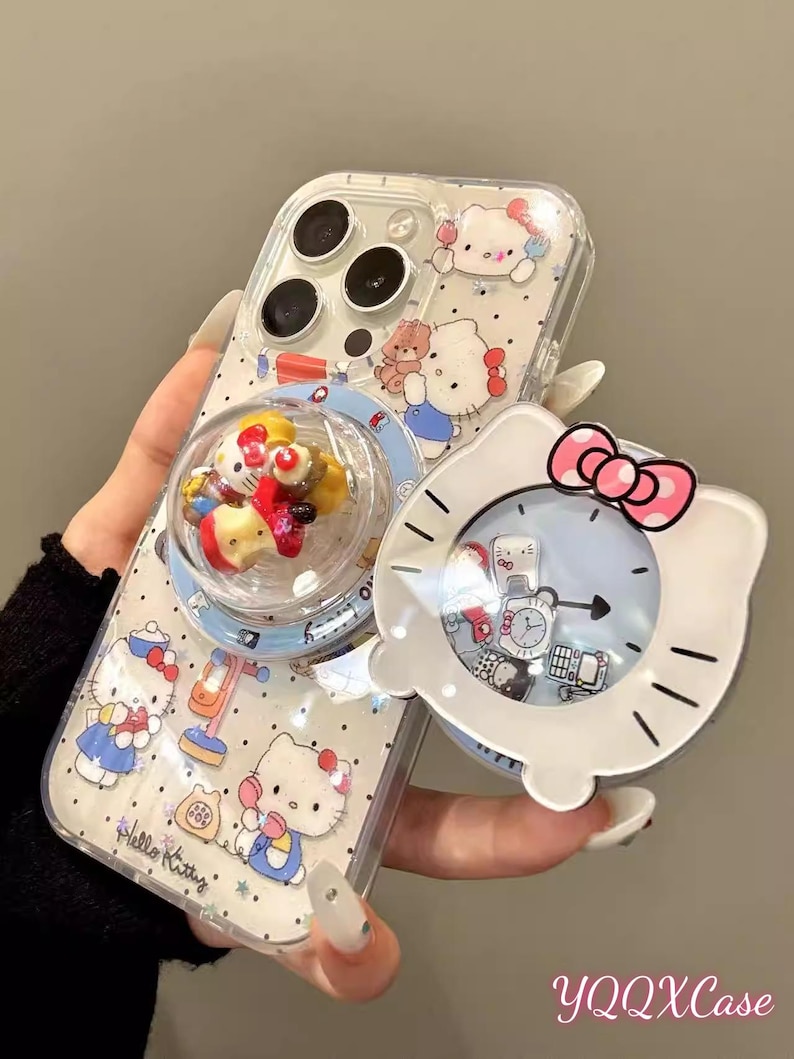 May include: Clear phone case featuring Hello Kitty designs and a pop-up bubble with miniature figures. The case has a white Hello Kitty-shaped clock with a pink bow and a rotating liquid-filled charm. The text "YQQXCase" is visible.