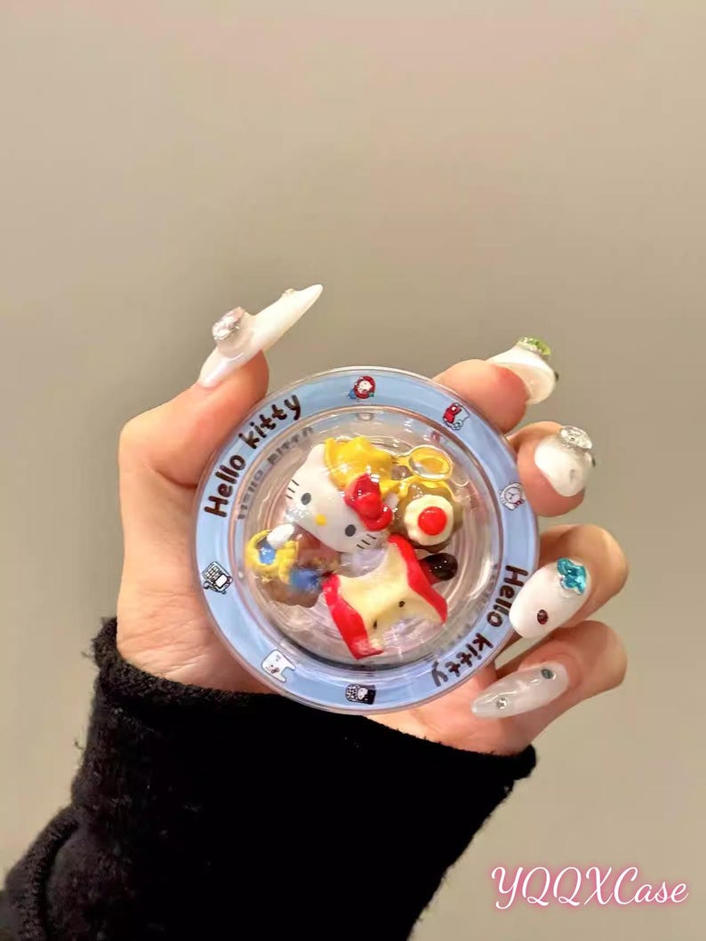 May include: A clear, round case with a blue rim featuring a Hello Kitty design. The case contains miniature Hello Kitty figures and food items. The text "Hello Kitty" is printed on the rim. The text "YQQXCase" is printed at the bottom.