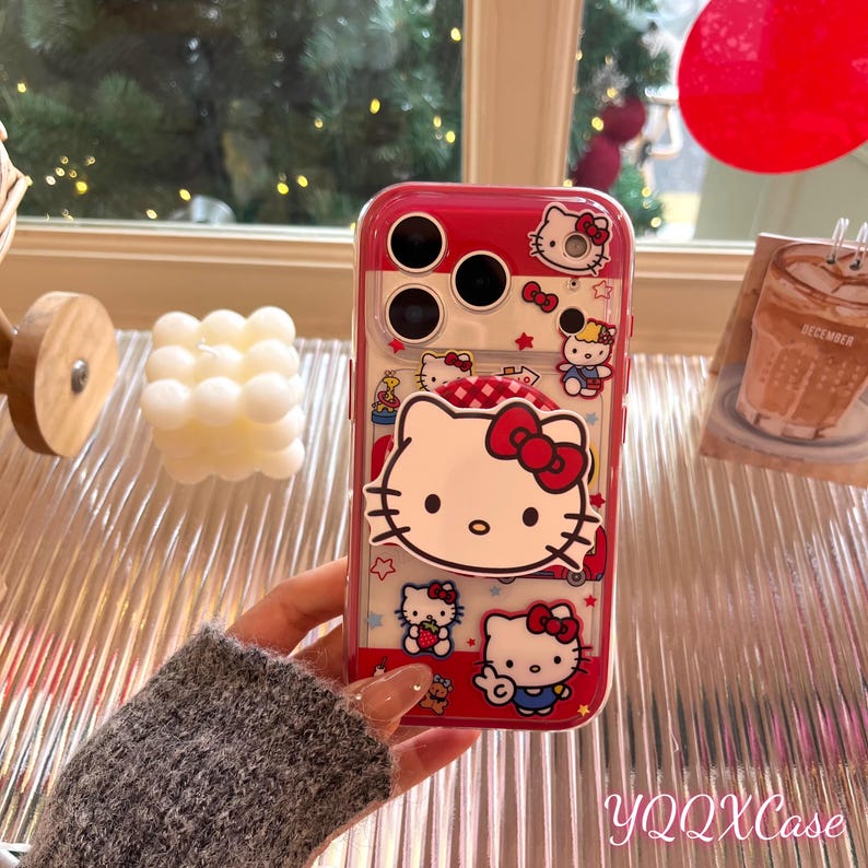 May include: A red and clear phone case with Hello Kitty illustrations. The case has a red frame and features various Hello Kitty images with red bows. The text "YQQXCase" is displayed at the bottom of the case.