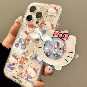 May include: Clear phone case with a Hello Kitty design. The case features multiple Hello Kitty illustrations and a matching white clock accessory with a pink bow. The text "Hello Kitty" is visible on the case.