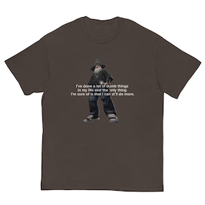 May include: A brown t-shirt featuring a graphic of a wizard with the text: "I've done a lot of dumb things in my life and the only thing I'm sure of is that I can st'll do more."