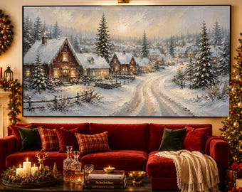 May include: A large rectangular wall art print depicting a snowy winter village scene with red houses, evergreen trees, and a winding path. The artwork is displayed above a red sectional sofa in a room with a fireplace and a decorated Christmas tree.