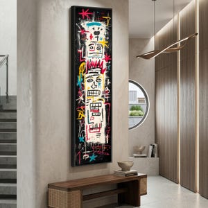 Pode incluir: Obra de arte abstrata emoldurada em preto. A obra apresenta três rostos estilizados com linhas arrojadas e cores vibrantes como vermelho, amarelo e azul sobre um fundo preto. A peça é montada em uma parede de tons neutros.