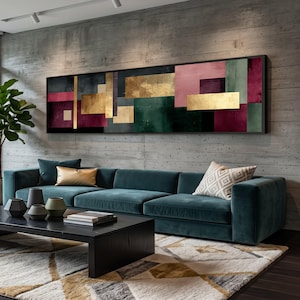 Könnte beinhalten: Abstrakte geometrische Wandkunst mit rechteckigen Formen in Gold, Rosa, Grün und Burgunderrot. Das Kunstwerk ist in Schwarz gerahmt und hängt über einem teal-farbenen Sofa. Der Raum umfasst auch einen schwarzen Couchtisch, dekorative Vasen und einen gemusterten Teppich.