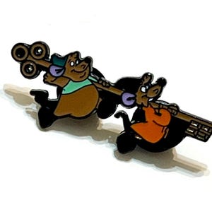 Könnte beinhalten: Ein farbenfroher Emaille-Pin mit zwei Zeichentrickfiguren, einem Bären und einer Maus, die einen großen Schlüssel tragen. Der Bär ist braun mit einem grünen Hemd und die Maus trägt ein orangefarbenes Hemd. Der Pin hat schwarze Umrisse und ist vor weißem Hintergrund.