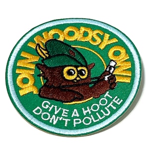 May include: A circular embroidered patch with a green background featuring a brown owl wearing a green hat. The text JOIN WOODSY OWL is stitched in yellow, and the text GIVE A HOOT DON'T POLLUTE is stitched in white along the bottom edge.