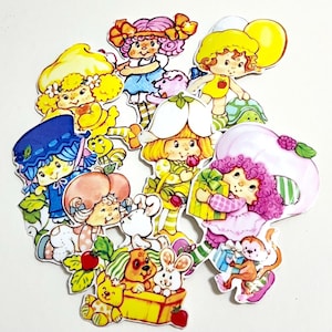 May include: A selection of colourful die-cut stickers showcasing cartoon characters. The stickers feature girls with diverse hairstyles and clothing, alongside animals and objects. The characters are in various poses, some holding gifts or balloons.