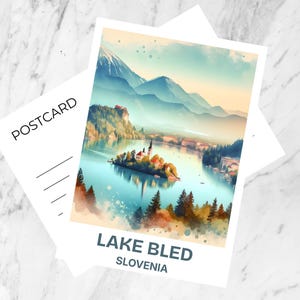 Può includere: Una cartolina con un dipinto ad acquerello del lago di Bled, in Slovenia, con una chiesa su un'isola. La cartolina è etichettata "Lake Bled Slovenia". C'è una cartolina vuota dietro.